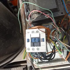 Widok z bliska na wyłącznik silnikowy Schneider z licznymi przewodami w skrzynce elektrycznej.