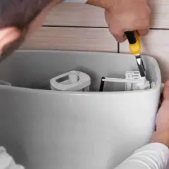 Instalator pokazuje, jak wyregulować spłuczkę, używając narzędzia do precyzyjnego ustawienia mechanizmu.