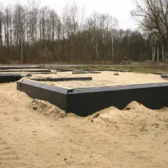 Fundament domu w piasku, przygotowany do wylania betonu. Czarna folia zabezpiecza przed wilgocią, a w przyszłości zapewni uszczelnienie przejścia rury przez fundament.