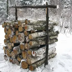 Stos drewna opałowego w śniegu, podtrzymywany przez drewniane podpory.