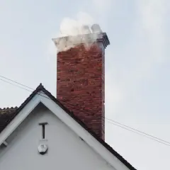 Dym wydobywa się z ceglanego komina, pokazując, że szachty co to jest, czyli kanały wentylacyjne, działają.