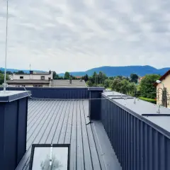 Nowoczesna instalacja odgromowa na dachu z blachy, chroniąca budynek przed burzą. Widok na góry w tle.