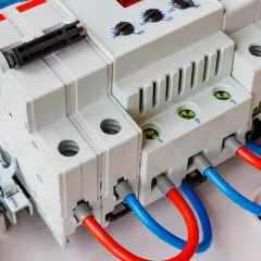 Nowoczesny ogranicznik przepięć AC z czerwonymi i niebieskimi przewodami, gotowy do ochrony instalacji elektrycznej.