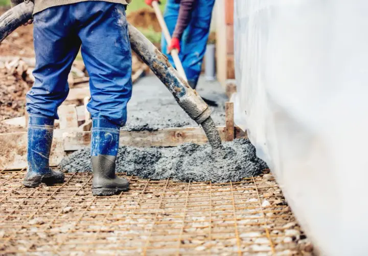 Pracownicy wylewają beton. Warto wiedzieć, ile waży kubik betonu, by zaplanować budowę.