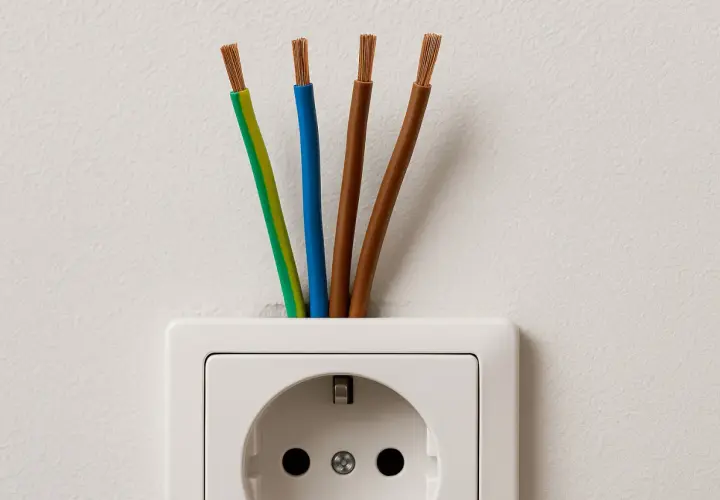 Cztery przewody wychodzące z gniazdka elektrycznego: zielono-żółty, niebieski i dwa brązowe. Jaki kabel do instalacji elektrycznej w domu?
