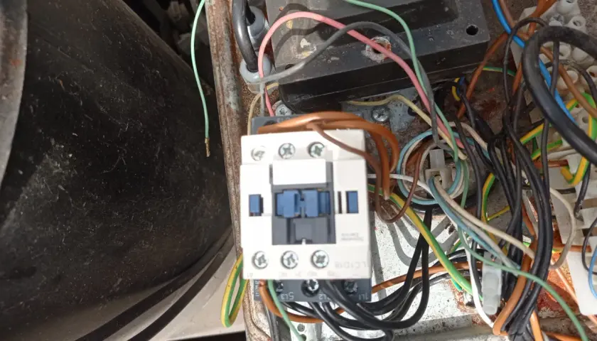 Widok z bliska na wyłącznik silnikowy Schneider z licznymi przewodami w skrzynce elektrycznej.