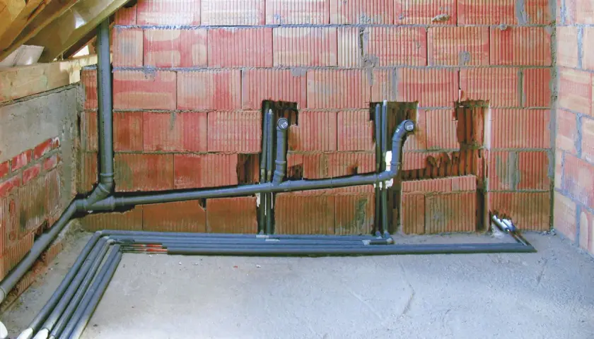 Instalacja hydrauliczna z rurami i kolankami, przygotowana do podłączenia, przypomina schemat odpowietrzenia szamba.
