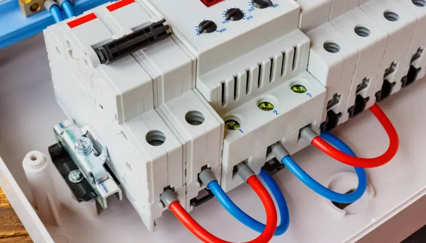 Nowoczesny ogranicznik przepięć AC z czerwonymi i niebieskimi przewodami, gotowy do ochrony instalacji elektrycznej.