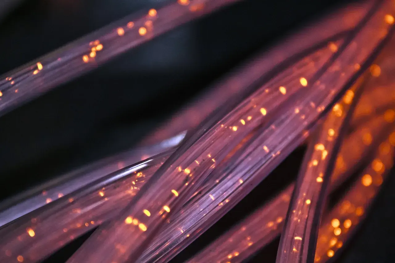 Światłowody FTTH, czyli "Fiber to the Home", to nowoczesna technologia dostarczania internetu. Widać tu ich skupisko, rozświetlone pomarańczowymi iskierkami.