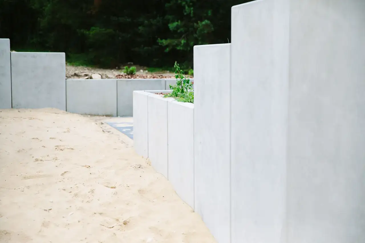 Nowy mur oporowy z betonu, z zielenią w środku. Pozwolenie na budowę wydane, teren przygotowany pod dalsze prace.