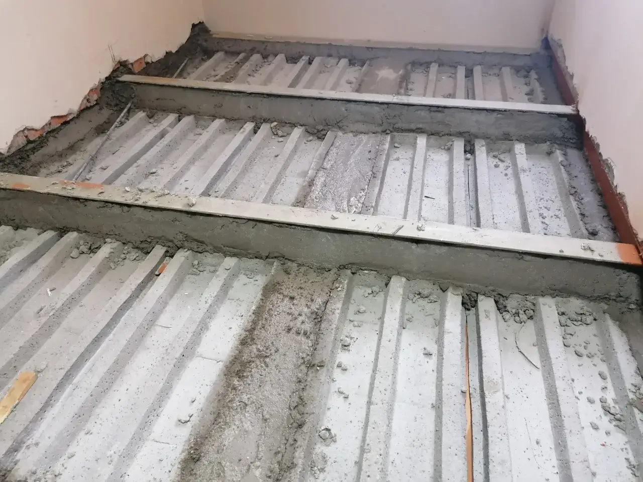 Wzmocnienie stropu w starym domu: betonowe belki i stalowe wsporniki tworzą solidną konstrukcję.