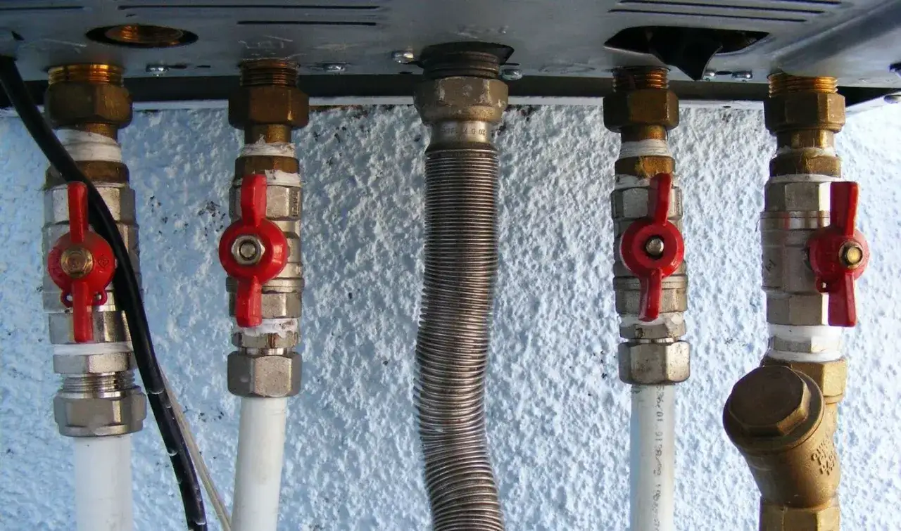 Zawory z czerwonymi uchwytami kontrolują ciśnienie w naczyniu przeponowym. Widoczne przyłącza hydrauliczne.