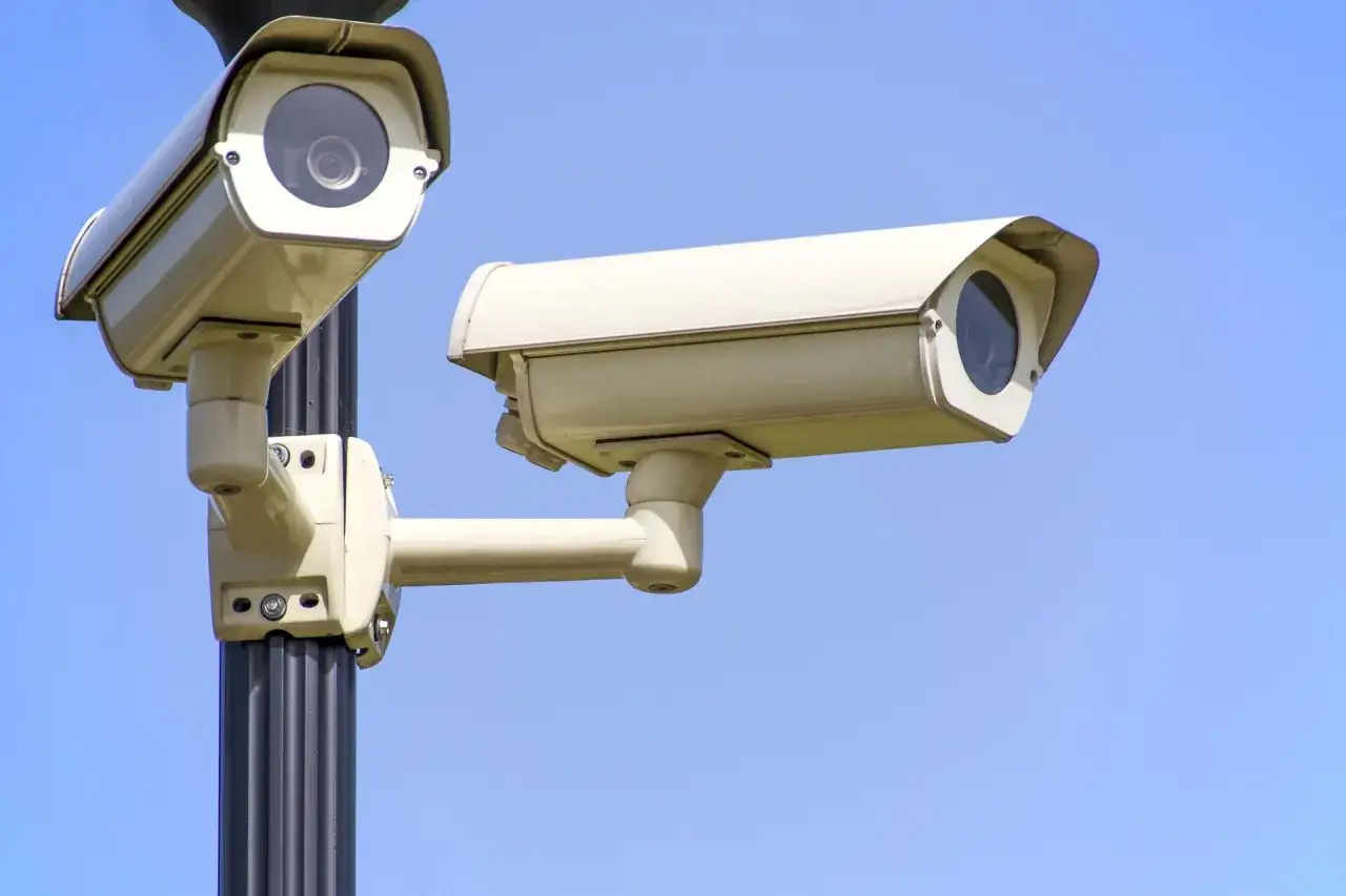 Dwie kamery CCTV na słupie, gotowe do monitorowania otoczenia. Zastanawiasz się, cctv co to? To systemy nadzoru wizyjnego.